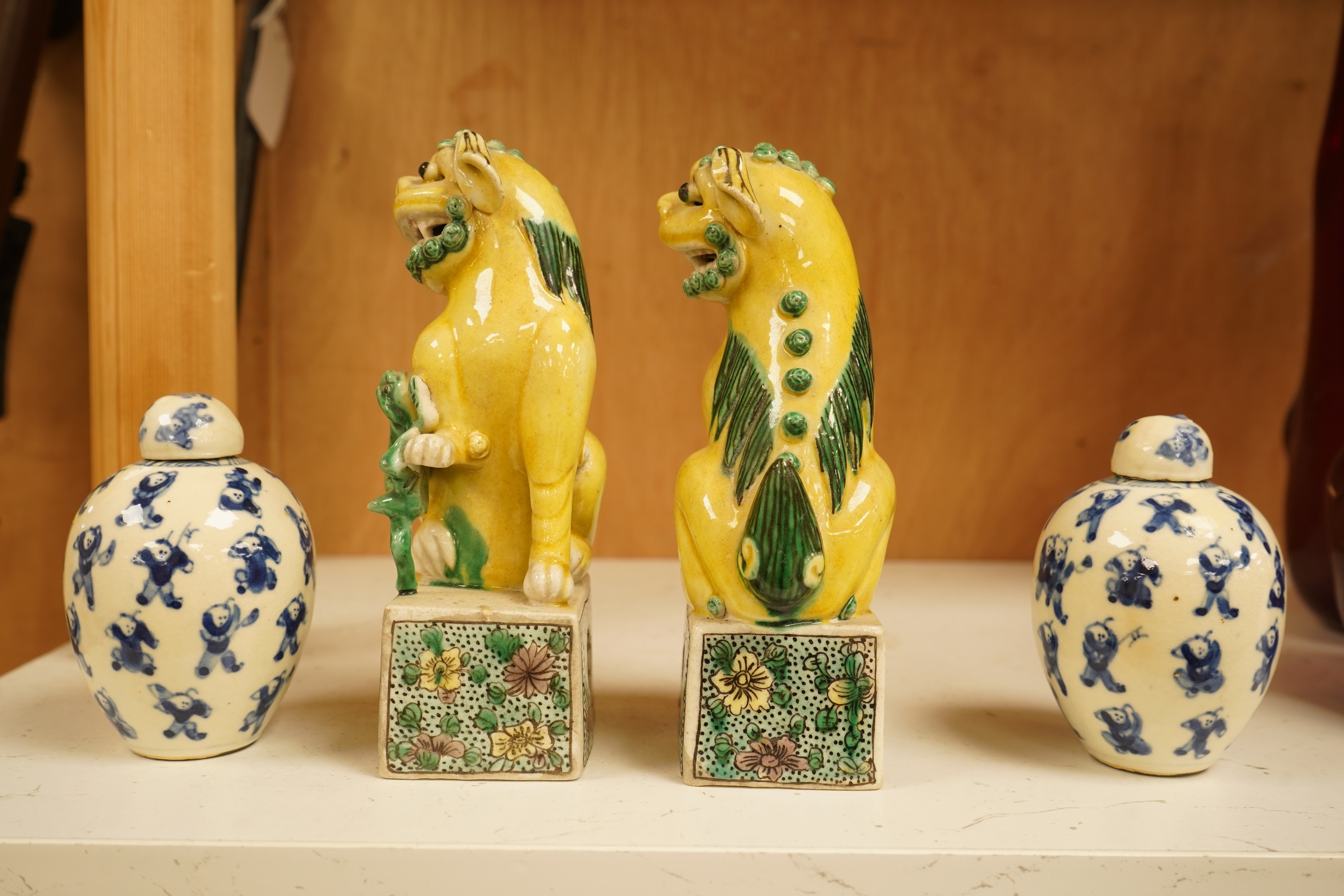 A pair of late 19th/early 20th century Chinese famille verte lion dogs and a similar pair of blue and white miniature ‘boys’ jars and covers, 15cm